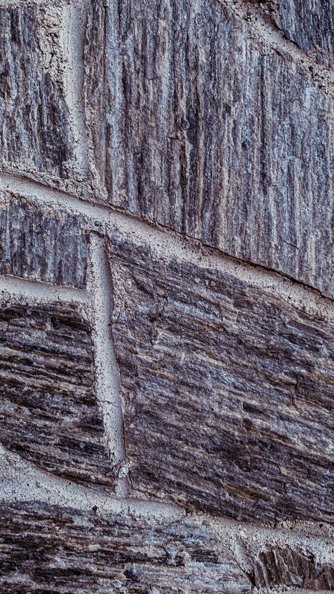 Detailed view of a textured stone wall highlighting rough patterns and grain.