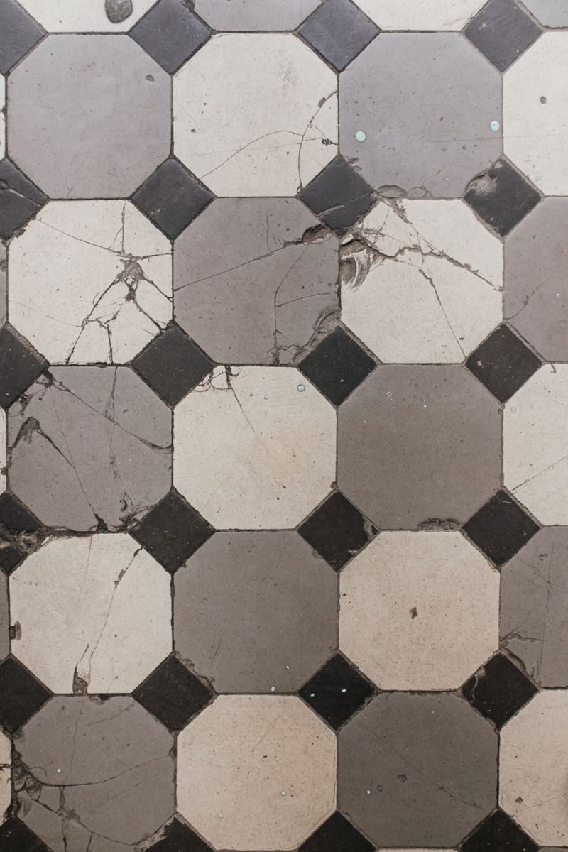 A cracked vintage geometric tiled floor featuring a classic octagonal pattern.