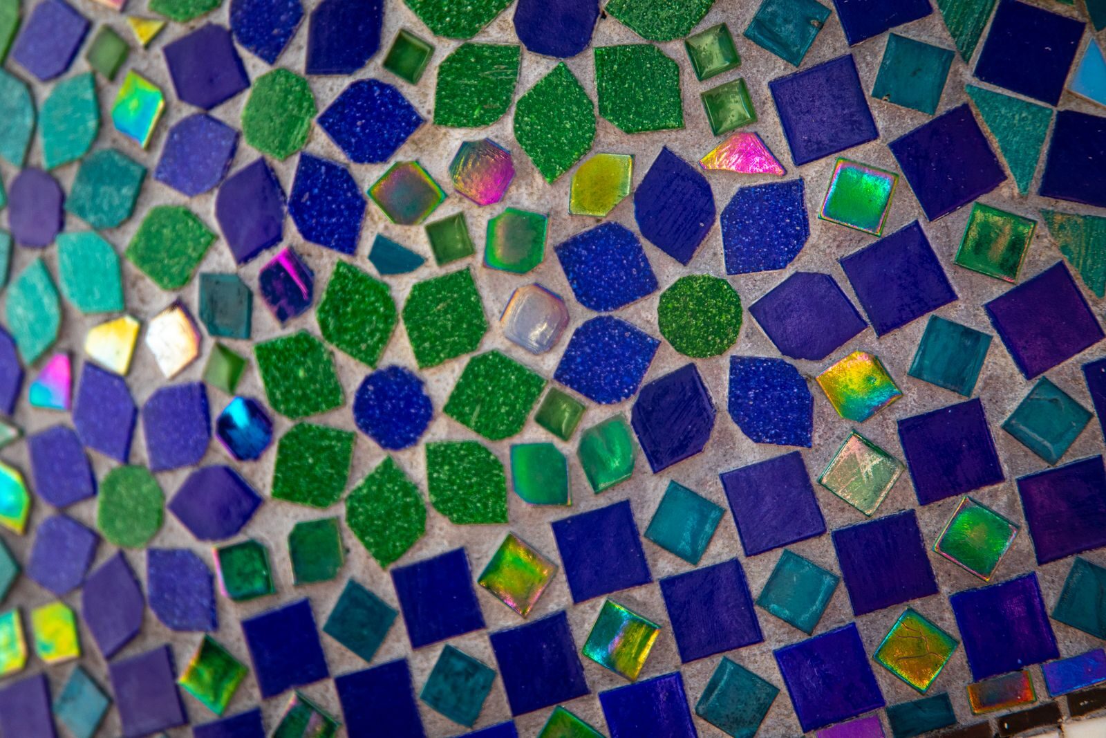 Colorful geometric mosaic featuring green, blue, and purple tiles in an abstract pattern.